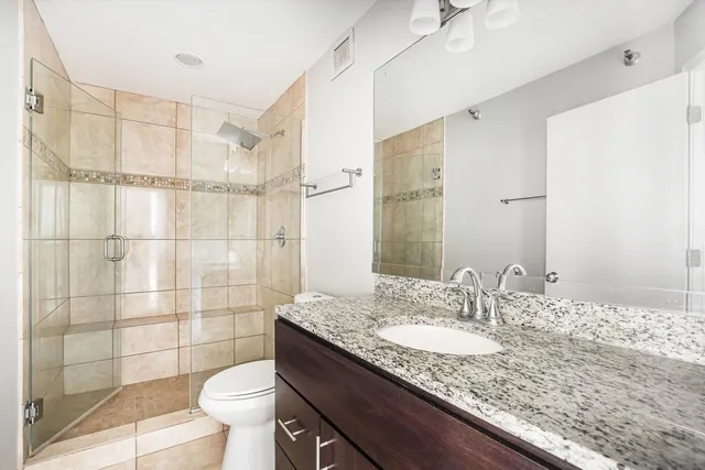 a bathroom with a granite countertop sink toilet a mirror and shower
