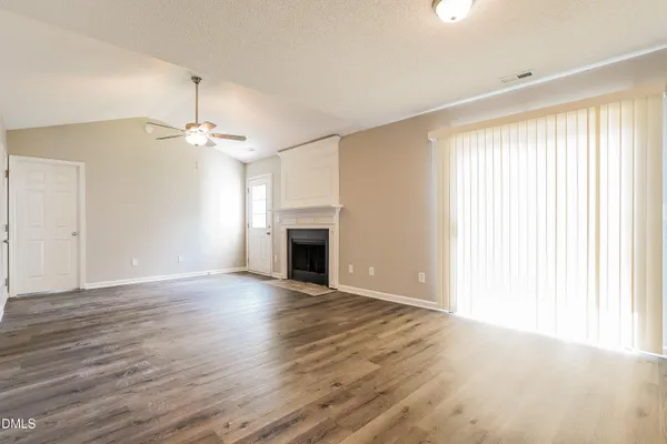a view of empty room with wooden floor and ceiling fan