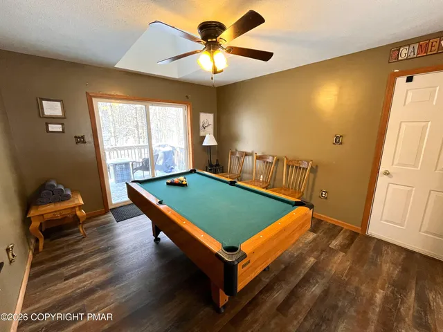 a room with wooden floor pool table and a ceiling fan