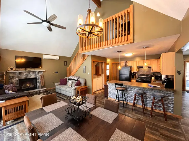 a living room with fireplace a flat screen tv and kitchen view