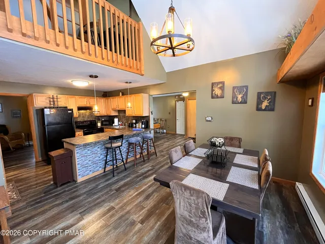 a kitchen with stainless steel appliances granite countertop a refrigerator a stove a sink a dining table and chairs with wooden floor