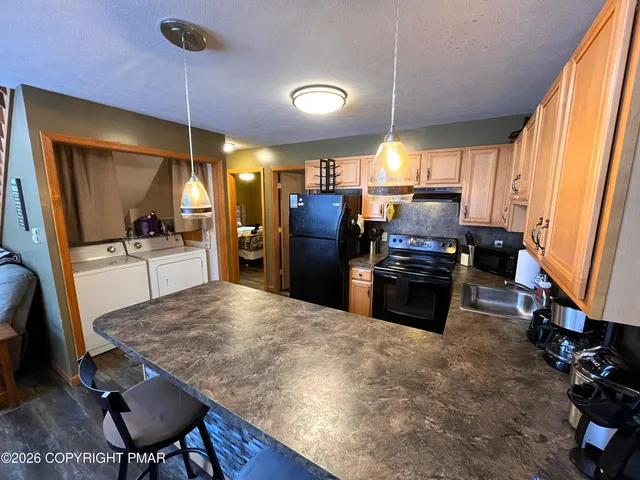 a living room with stainless steel appliances granite countertop furniture a refrigerator a sink a counter top space and cabinets