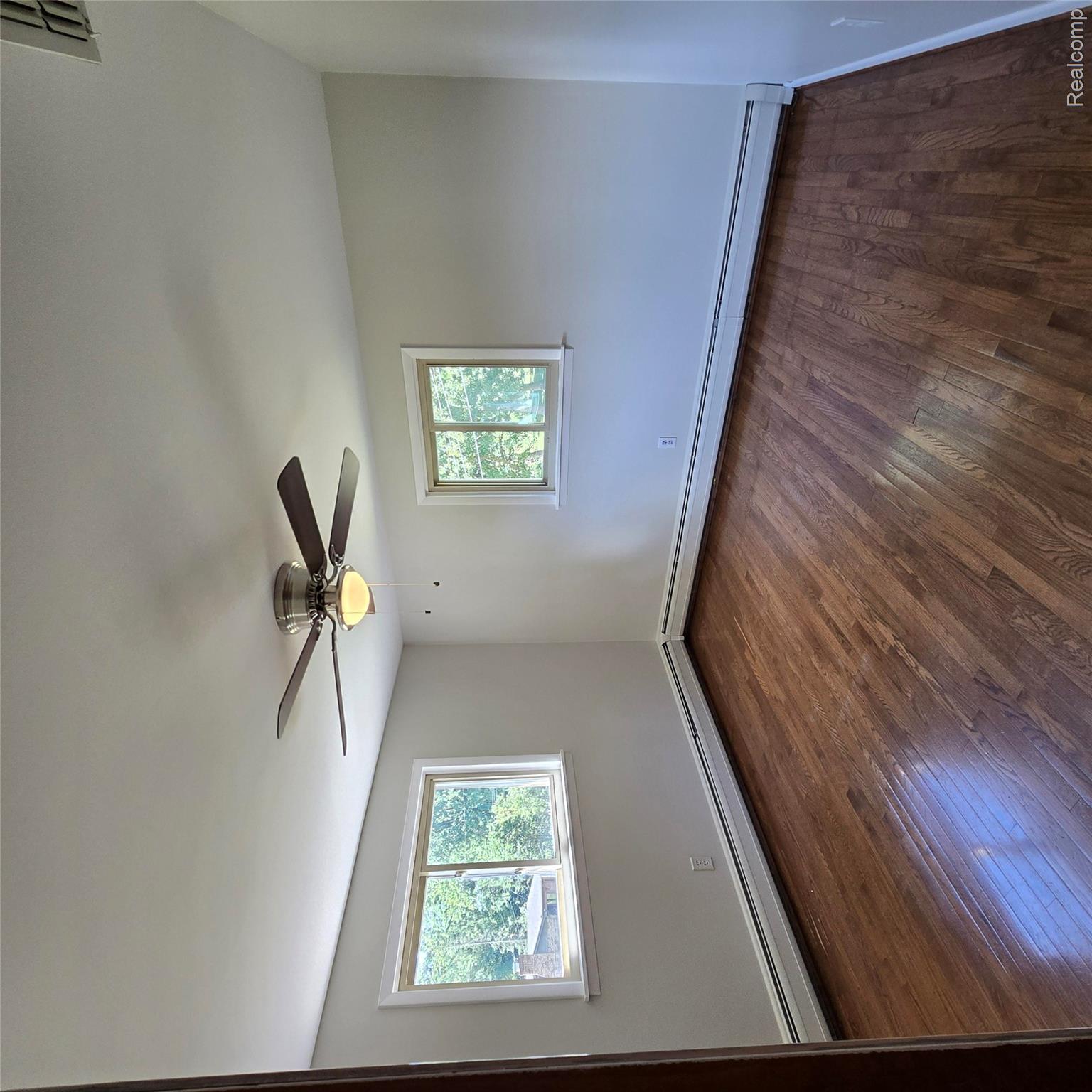 311 Nevada Avenue Rochester, MI 48309 - Photo 34 of 70 Spacious room featuring wood-finish flooring, two windows, baseboard heating, a ceiling fan with integrated lighting, and neutral wall finishes