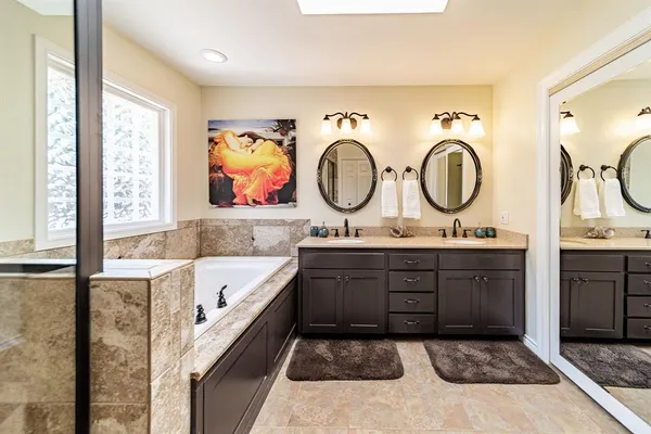 a spacious bathroom with a tub sink and mirror