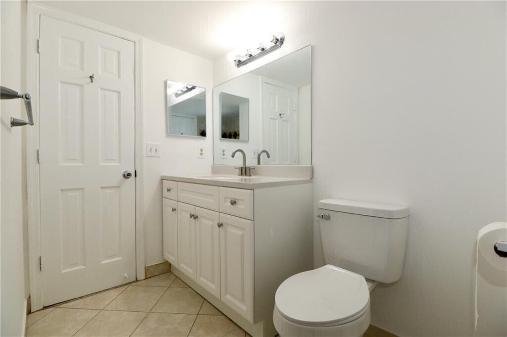 9915 Sandalfoot Boulevard, Unit 408 Boca Raton, FL 33428 - Photo 13 of 19 a bathroom with a toilet a sink a mirror and vanity
