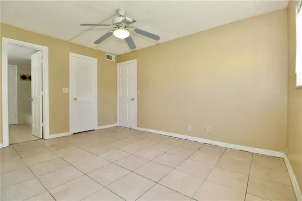 a view of an empty room and chandelier fan