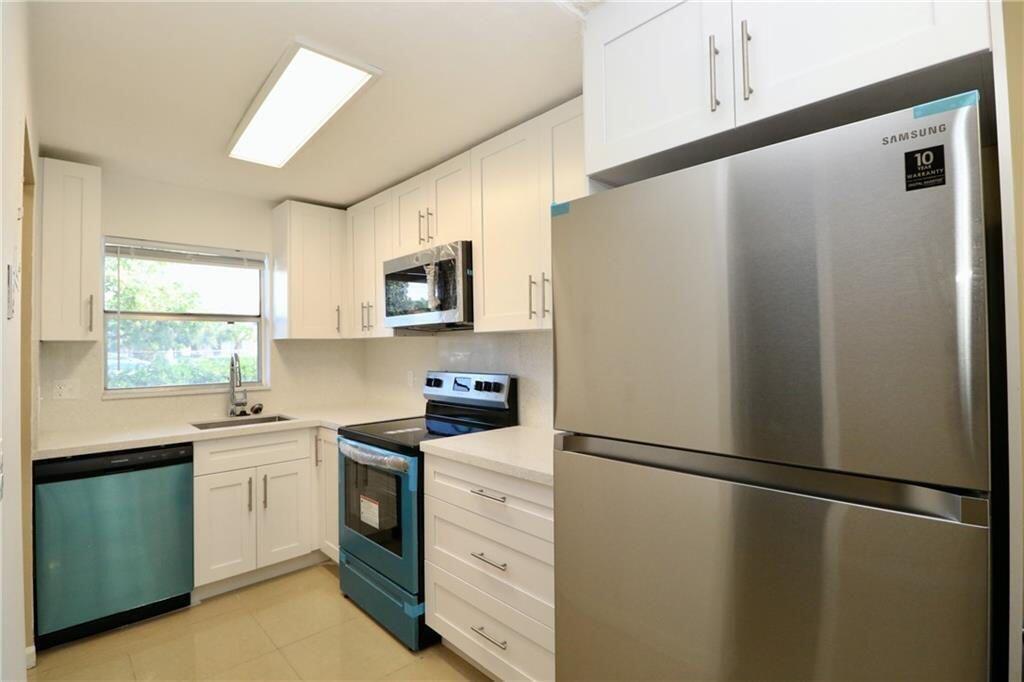 9915 Sandalfoot Boulevard, Unit 408 Boca Raton, FL 33428 - Photo 4 of 19 a kitchen with stainless steel appliances a refrigerator sink and microwave