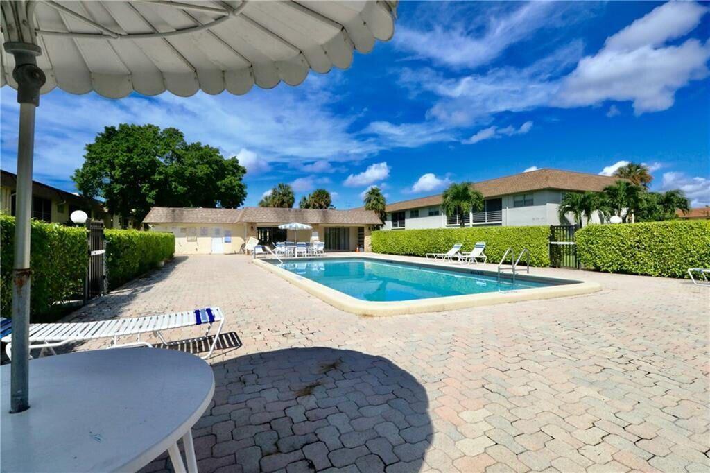 9915 Sandalfoot Boulevard, Unit 408 Boca Raton, FL 33428 - Photo 7 of 19 a view of a white house with a yard
