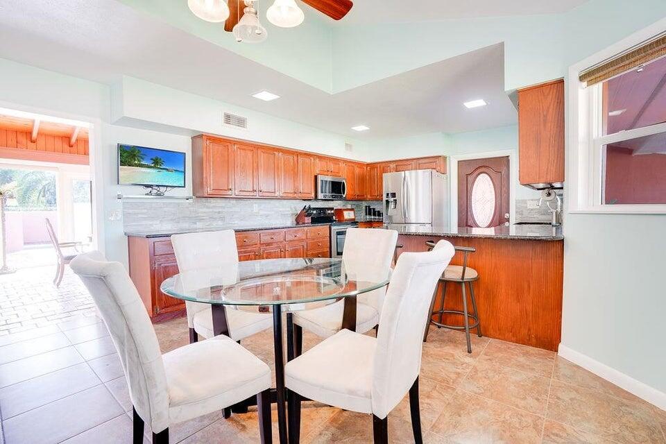 7600 Immokolee Road Fort Pierce, FL 34951 - Photo 18 of 32 a kitchen with stainless steel appliances granite countertop a stove a sink dishwasher a dining table and chairs with wooden floor