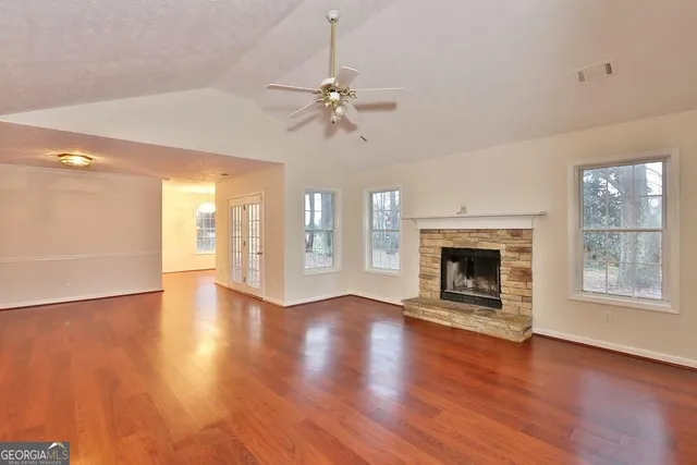 a view of a livingroom with wooden floor a fireplace and windows