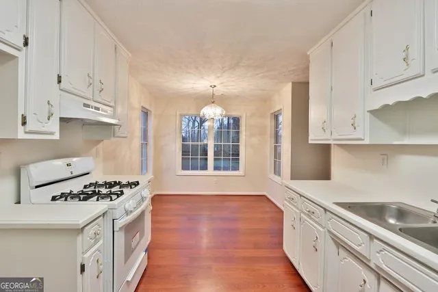a kitchen with granite countertop a sink stove and cabinets