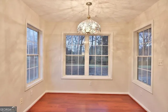 a view of an empty room with wooden floor and windows