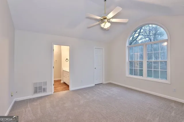 an empty room with chandelier fan and windows