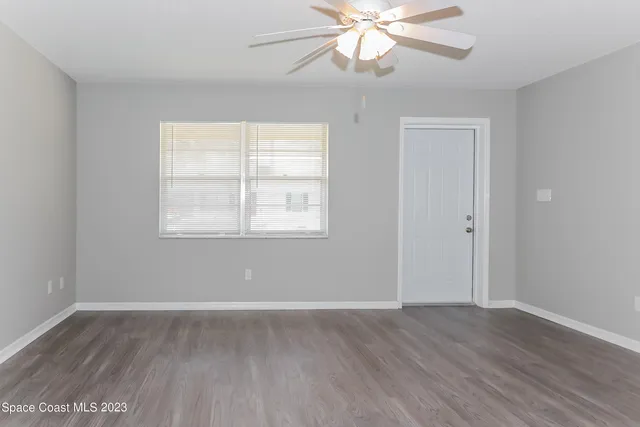 an empty room with wooden floor fan and windows