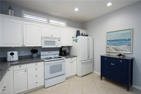 a kitchen with white cabinets and refrigerator
