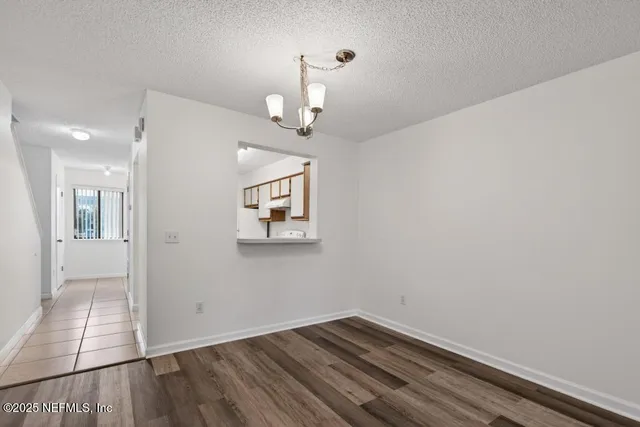 a view of a hallway with wooden floor and a chandelier