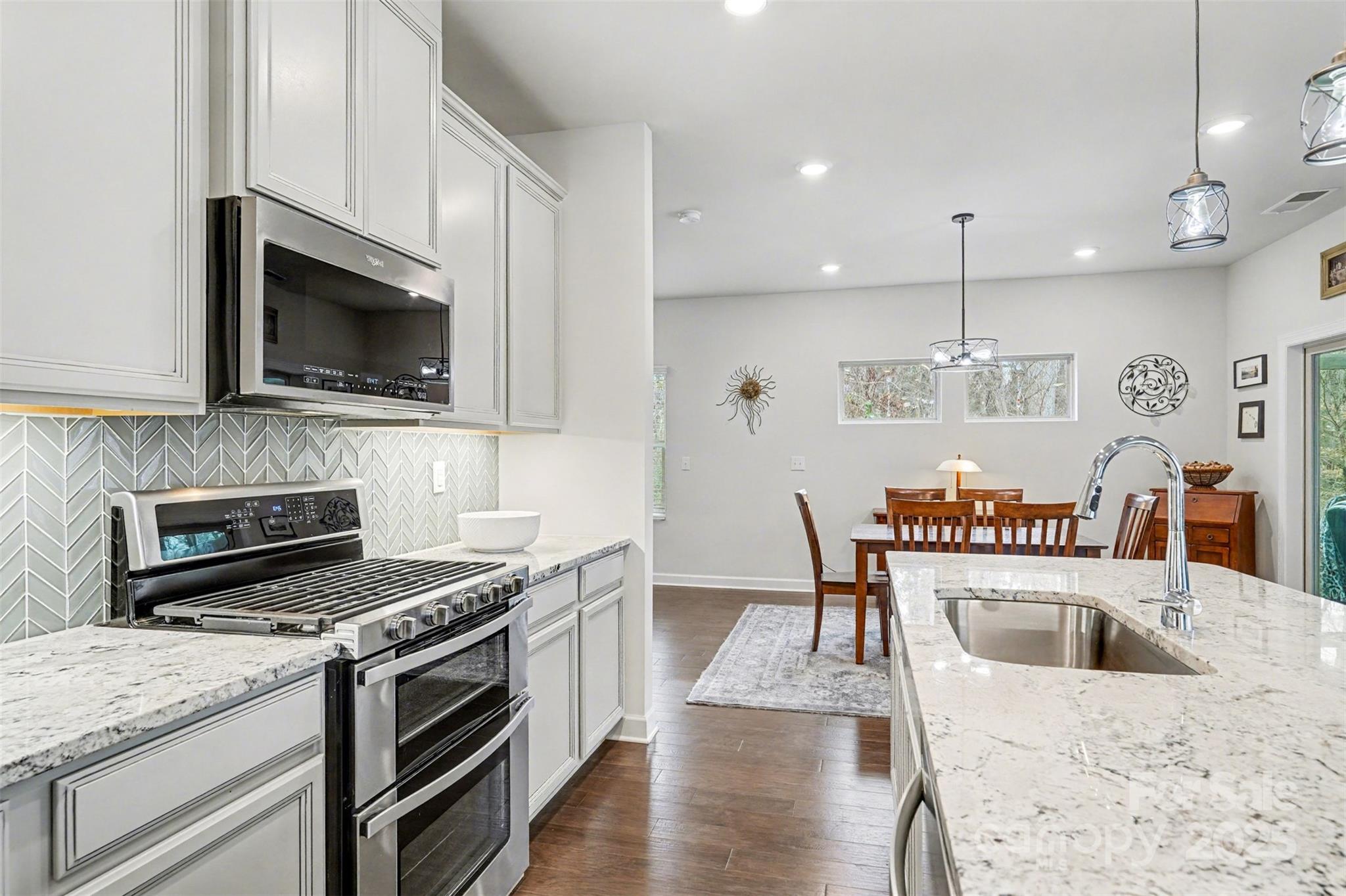 6220 Hailstone Road Charlotte, NC 28215 - Photo 10 of 37 a kitchen with stainless steel appliances kitchen island granite countertop a stove a sink a microwave and wooden cabinets