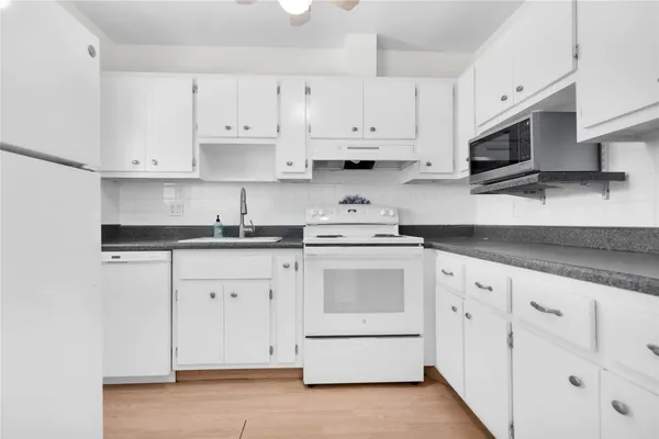 a kitchen with stainless steel appliances granite countertop white cabinets a sink and dishwasher