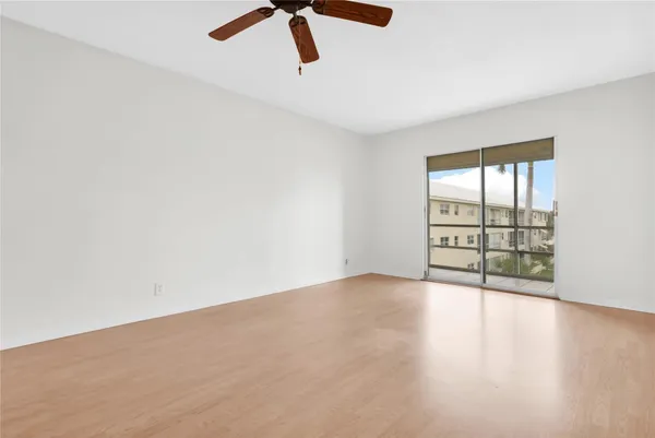an empty room with chandelier fan and windows