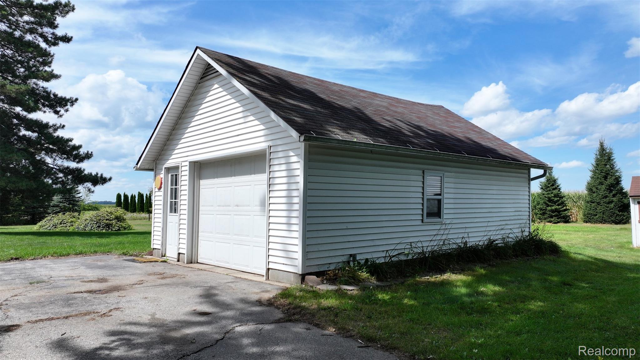 12930 Wilkinson Road Freeland, MI 48623 - Photo 14 of 76 Detached garage with white siding, an asphalt shingle roof, a single garage door, and a side entry door