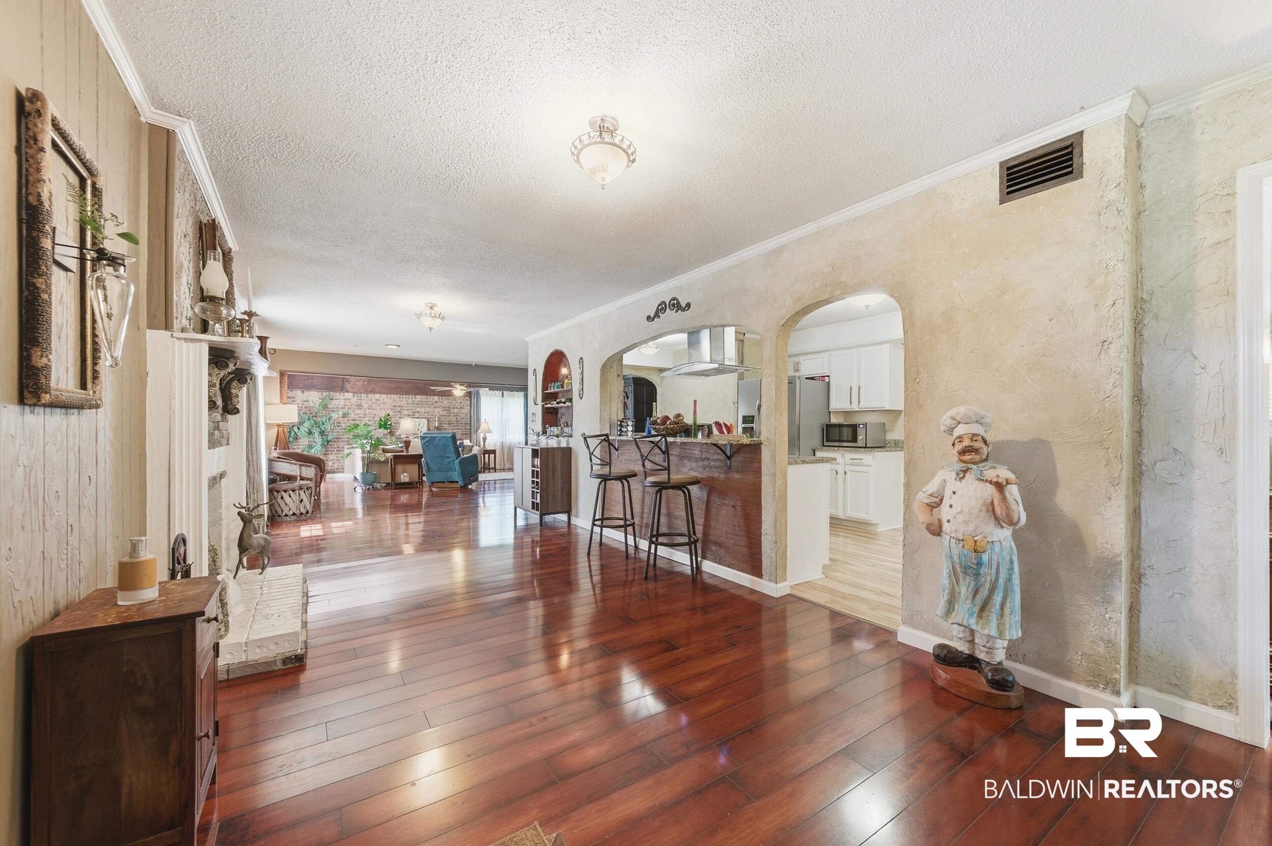 51620 Robert White Road Bay Minette, AL 36507 - Photo 26 of 81 Expansive open-concept living area featuring rich wood-finish flooring, crown molding, and a built-in fireplace with a stone hearth