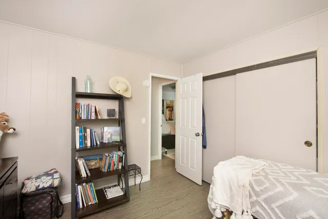 a bedroom with a bed and a bookshelf with wooden floor