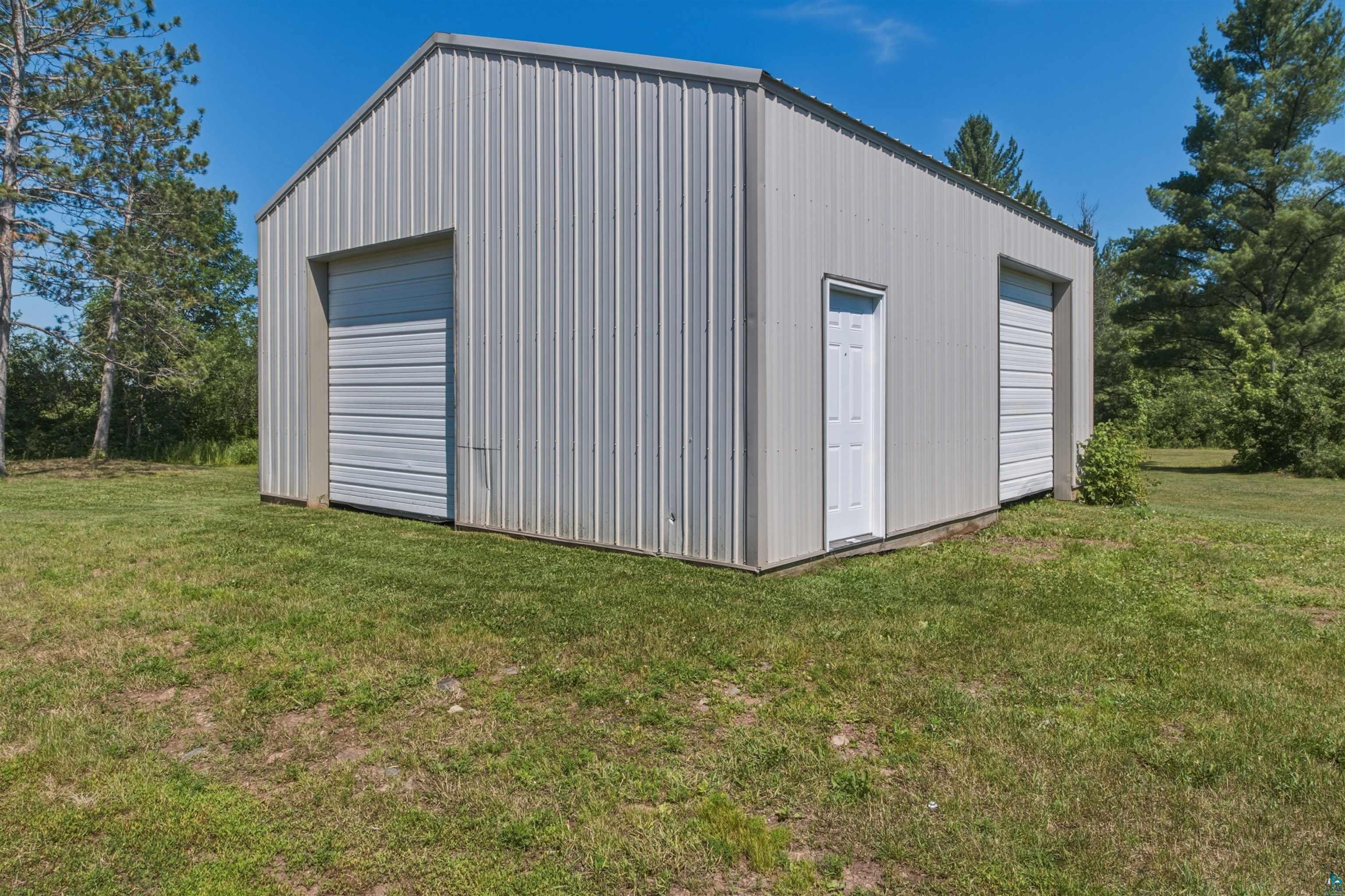 64260 Jolma Road Ashland, WI 54806 - Photo 24 of 35 Corrugated metal utility building featuring two roll-up garage doors, a side entry door, and a pitched roof
