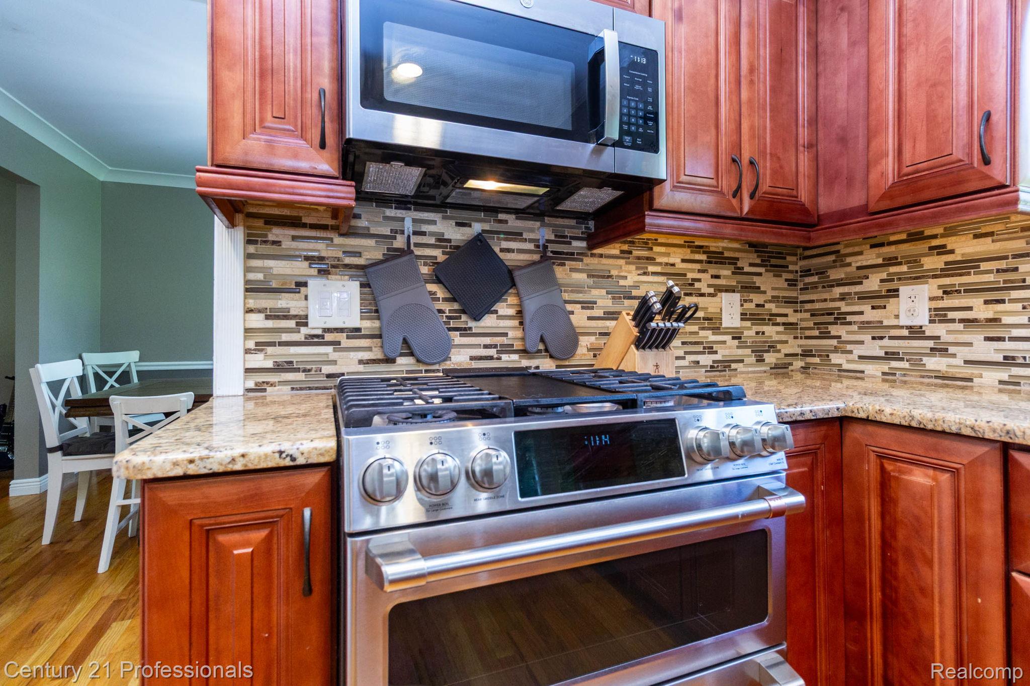 671 Bridgestone Drive Rochester, MI 48309 - Photo 15 of 50 Kitchen featuring stainless steel range with double ovens, stainless steel microwave, stone countertops, and a mosaic tile backsplash