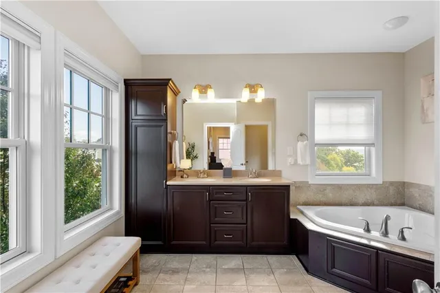 a bathroom with a tub a sink and a window