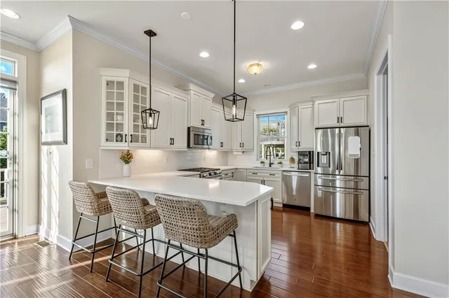 a kitchen with stainless steel appliances granite countertop a refrigerator a sink a stove and white cabinets with wooden floor