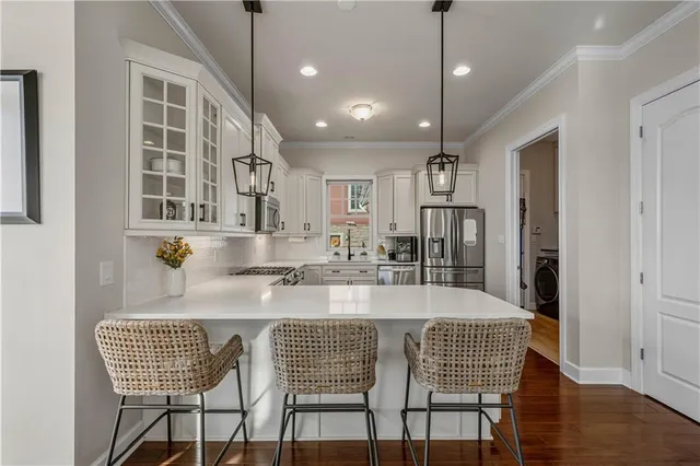 a large kitchen with granite countertop a dining table chairs stainless steel appliances and cabinets