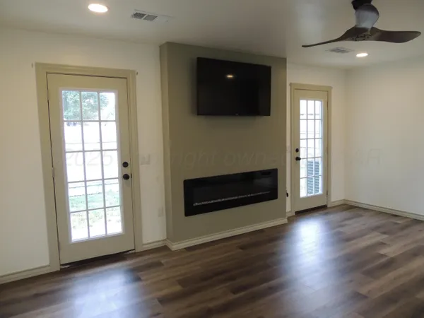 an empty room with wooden floor fireplace and windows