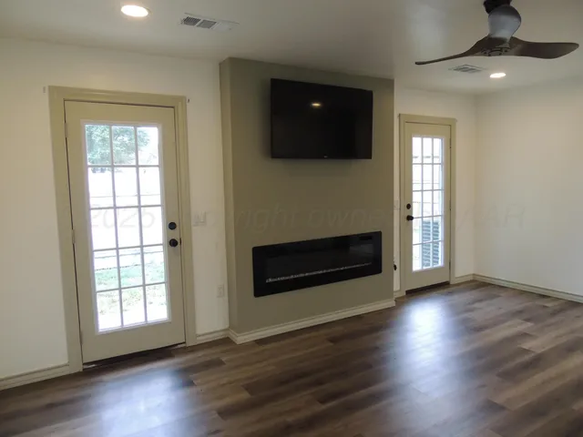 an empty room with wooden floor fireplace and windows