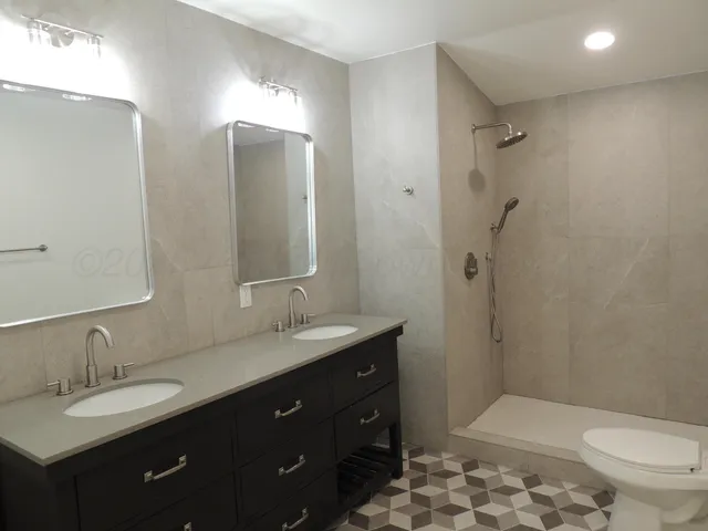 a bathroom with a double vanity sink mirror and toilet