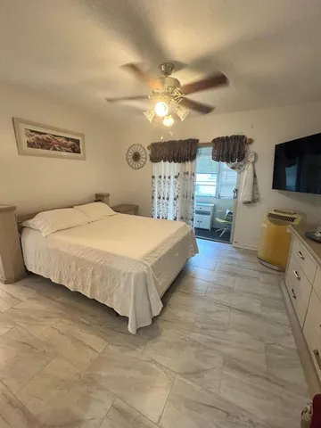 a bedroom with a bed and a flat tv screen on dresser