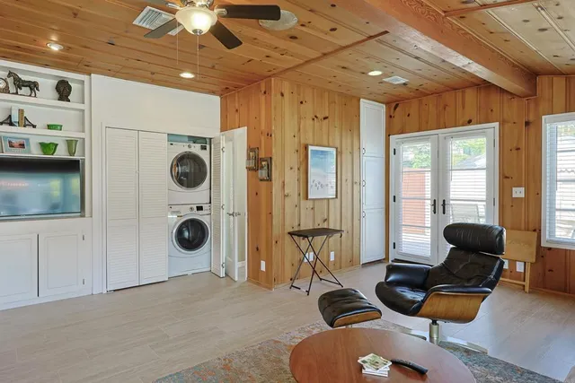a living room with furniture a flat screen tv and a refrigerator