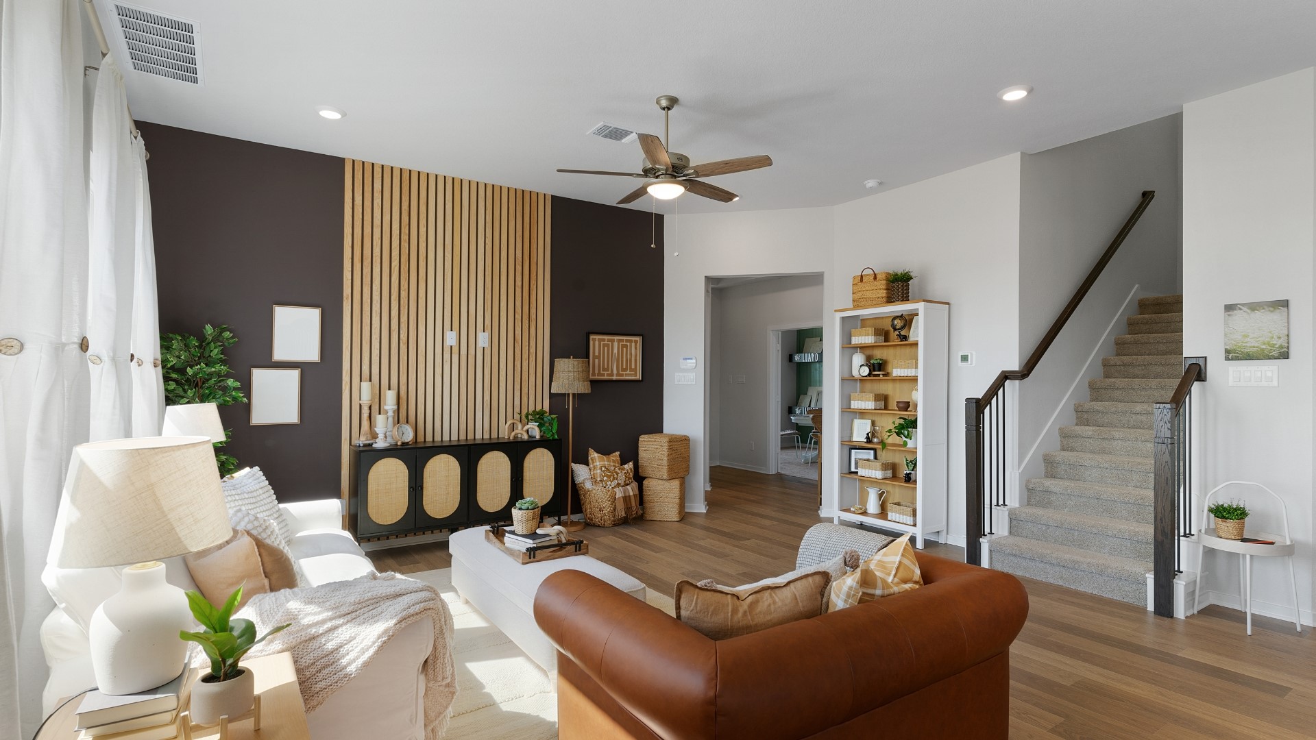25812 Jasmine Sprig Lane Elgin, TX 78621 - Photo 5 of 33 Natural light floods this inviting living area, showcasing rich hardwood floors and a striking accent wall.