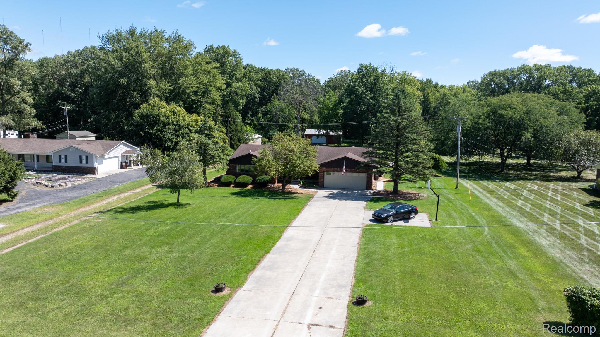 12900 Maxwell Road Carleton, MI 48117 - Photo 6 of 59 Single-story residence with a brick facade and attached garage, situated on a substantial grassy lot with mature trees