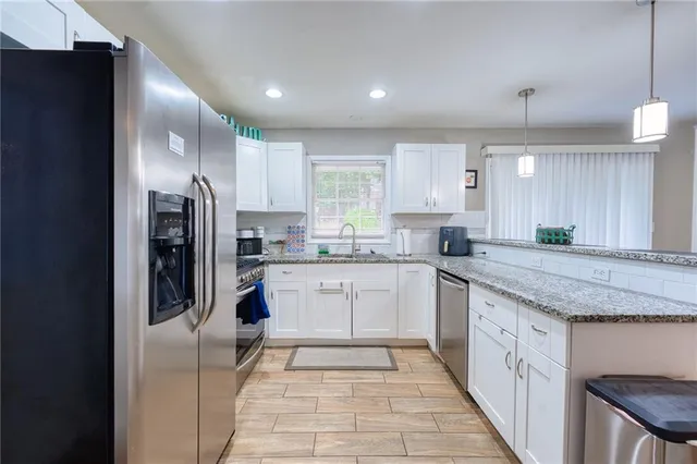 a kitchen with stainless steel appliances granite countertop a refrigerator a sink dishwasher and a stove with wooden floor