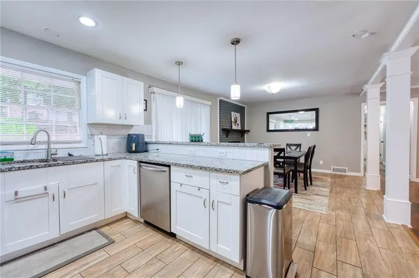 a kitchen with stainless steel appliances granite countertop wooden cabinets a sink a stove a dining table and chairs