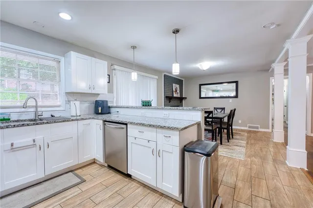 a kitchen with stainless steel appliances granite countertop wooden cabinets a sink a stove a dining table and chairs