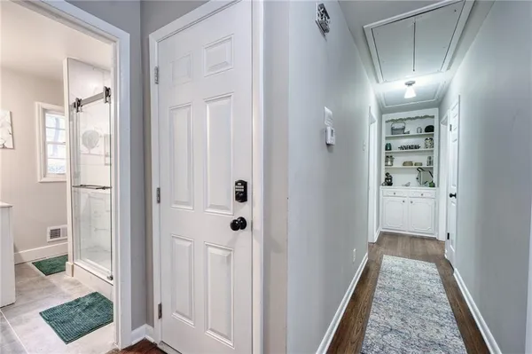 a view of a hallway with wooden floor and a bathroom