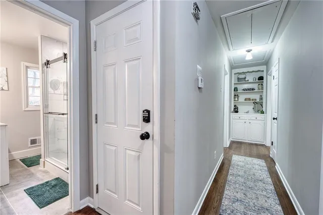 a view of a hallway with wooden floor and a bathroom