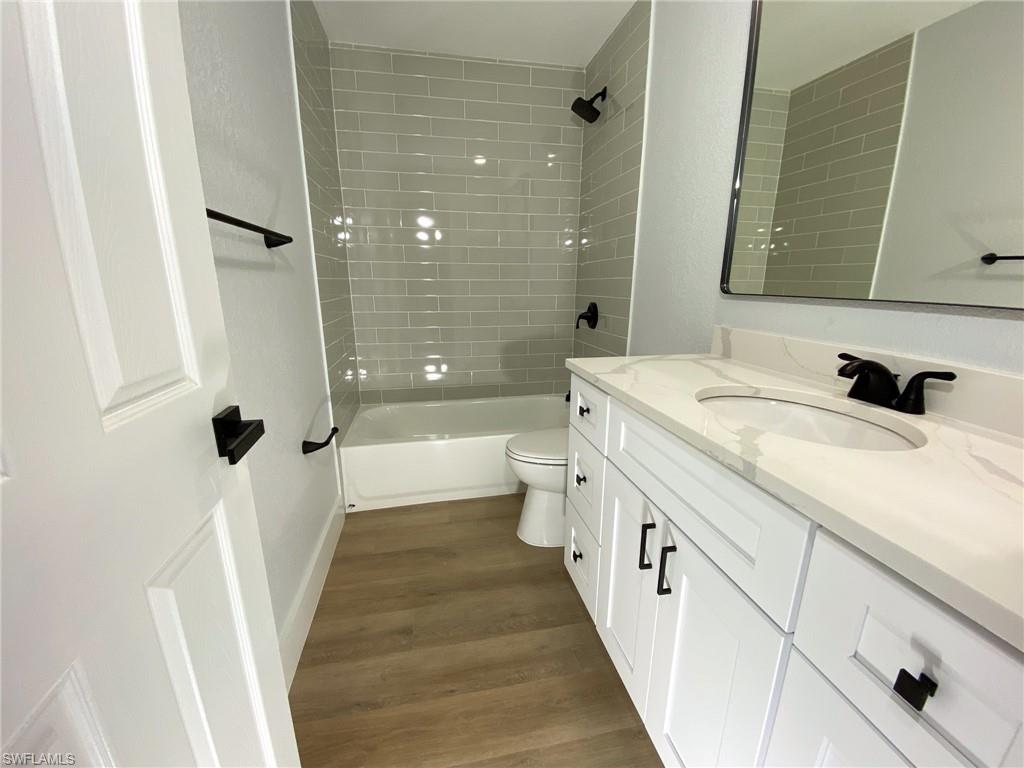 4180 Looking Glass Lane, Unit 4108 Naples, FL 34112 - Photo 14 of 21 Bathroom featuring toilet, vanity, shower / bathtub combination, and wood finished floors