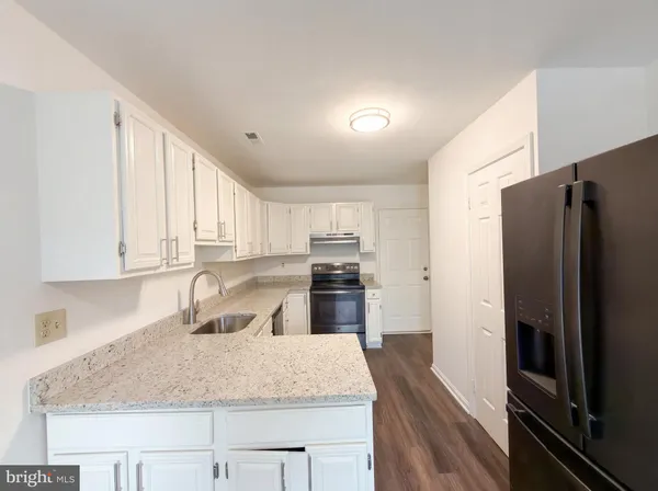 a kitchen with granite countertop a refrigerator stove and sink