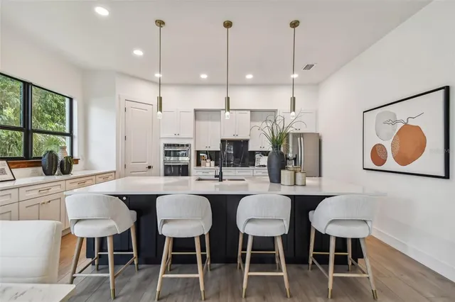 a kitchen with stainless steel appliances granite countertop a dining table chairs and white cabinets