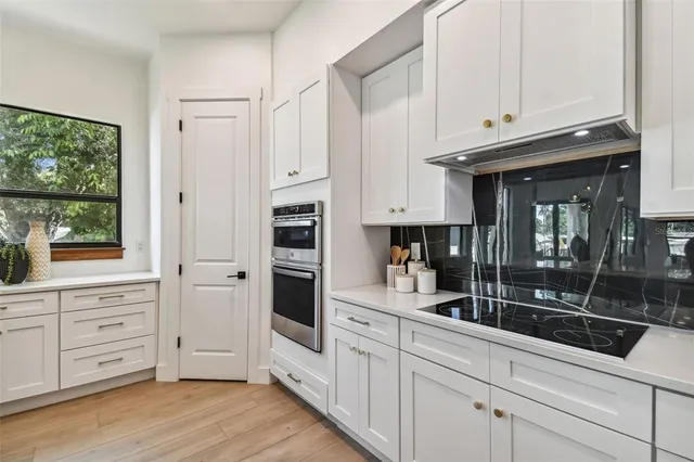 a kitchen with stainless steel appliances white cabinets and wooden floors
