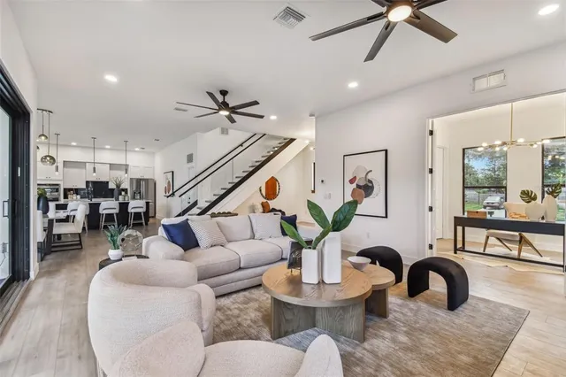 a living room with furniture kitchen view and a wooden floor