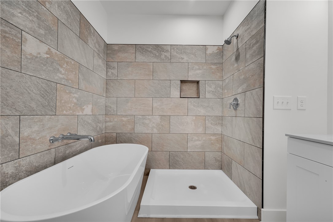 659 White Oak Farms Road Tamassee, SC 29686 - Photo 34 of 50 Textured tile walls accent a modern soaking tub alongside a clean-lined walk-in shower setup.