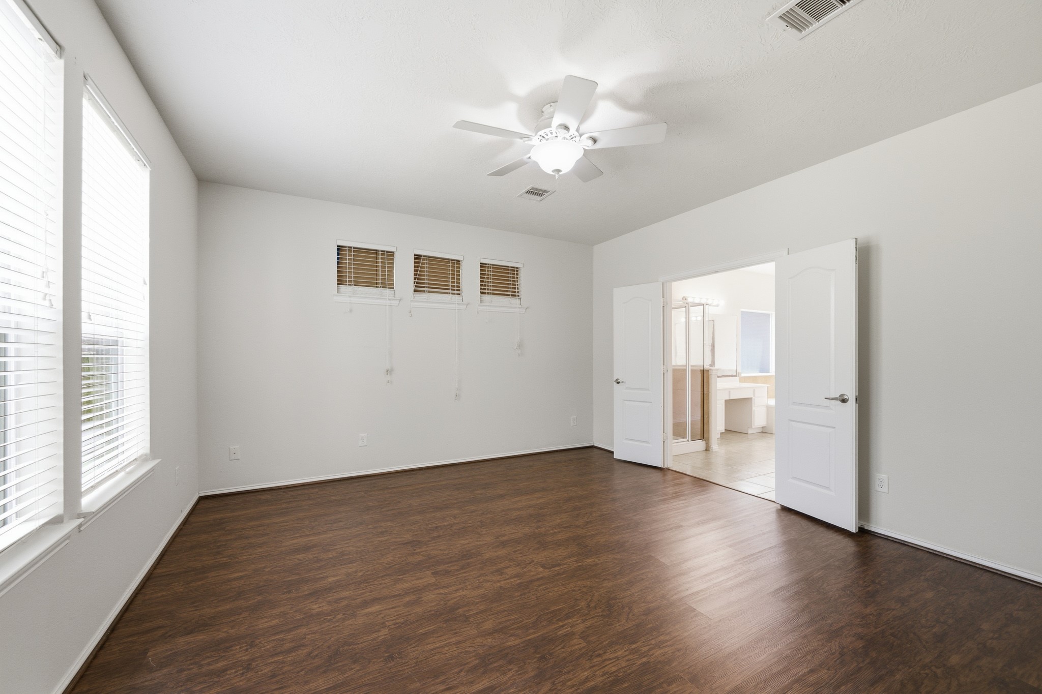 2117 Rushing Spring Drive Pearland, TX 77584 - Photo 21 of 42 Spacious primary bedroom featuring elegant hardwood floors, abundant natural light, and seamless access to a luxurious ensuite bathroom.